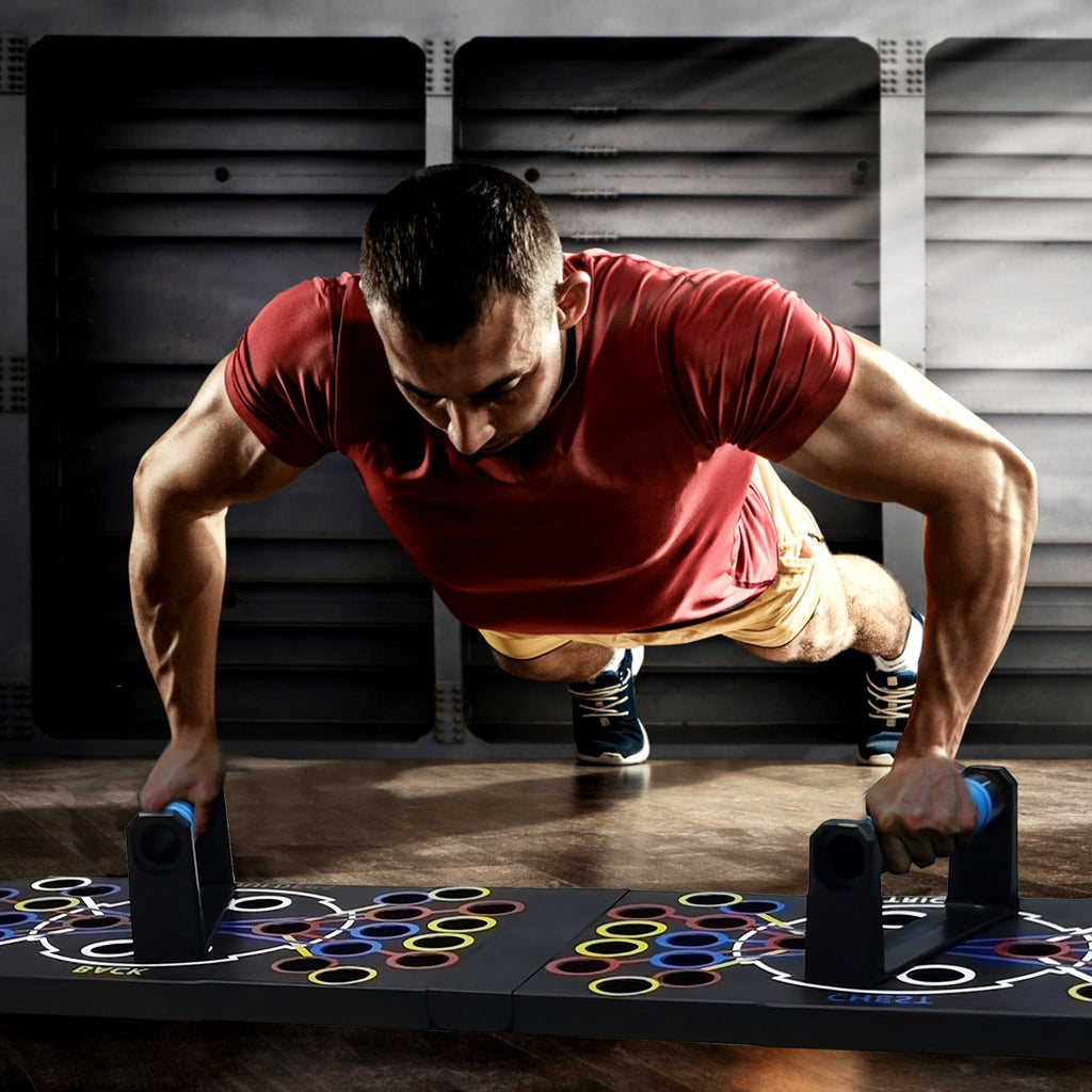 Man in red shirt and yellow shorts performing push-ups with dumbbells on a colorful mat.